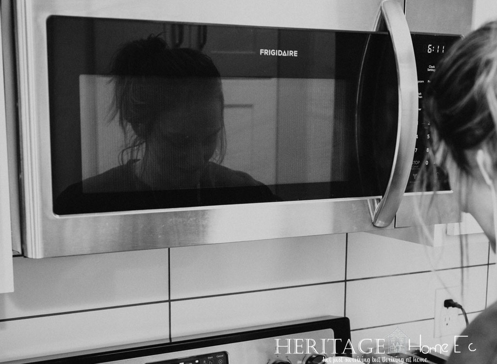 woman cooking at stove with wall mounted above-the-range microwave