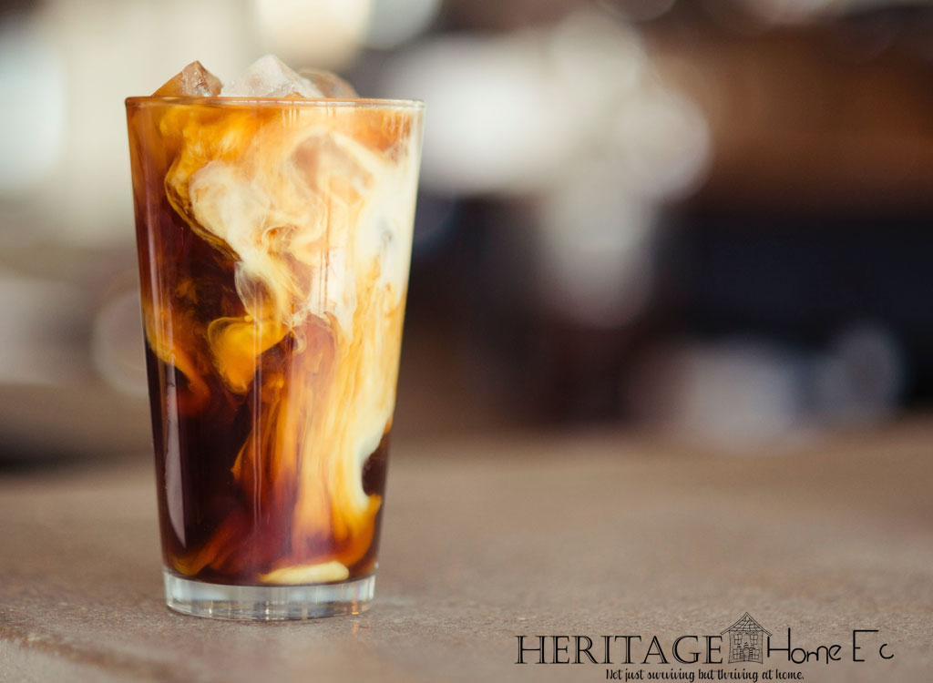 perfect iced coffee with swirled milk in glass on bokeh background