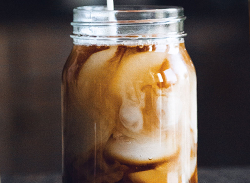 swirled iced coffee and milk in jar mason jar on dark background