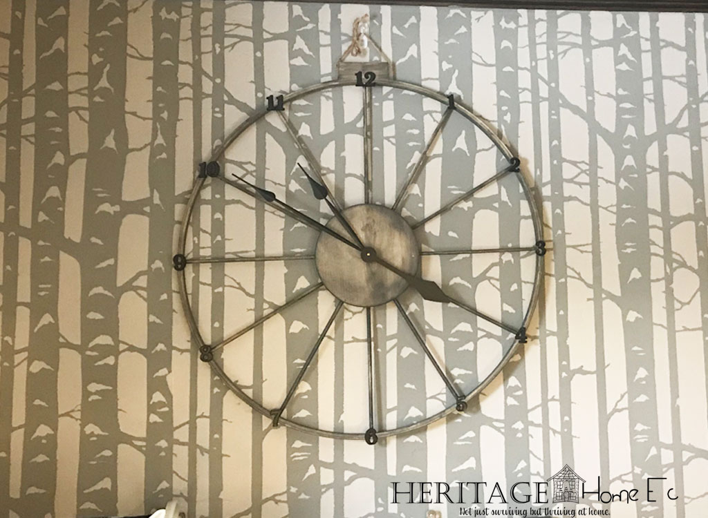 completed stained farmhouse wagon wheel clock on stenciled wall