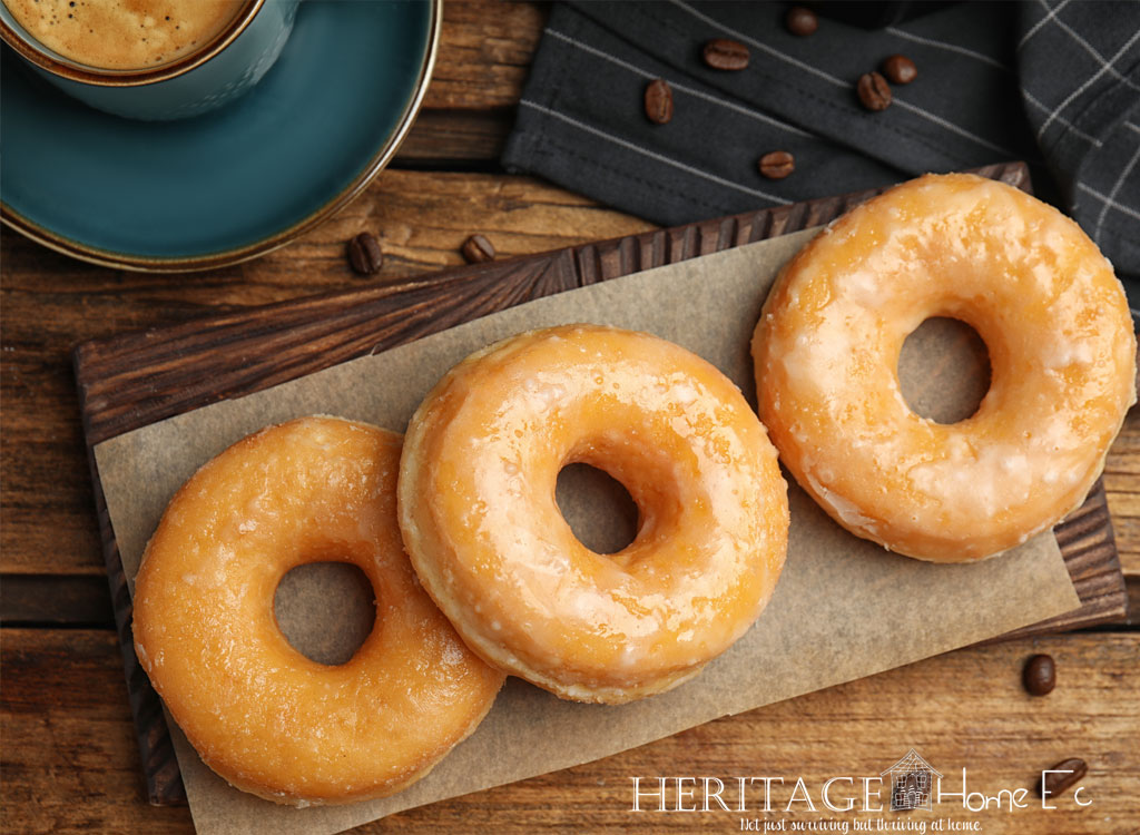 line of glazed doughnuts on paper with coffee beans on wooden background
