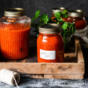 salsa and tomato juice in a wood crate on dark background
