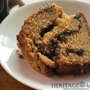 close up of a piece of coffee cake on wood table with a cup of coffee