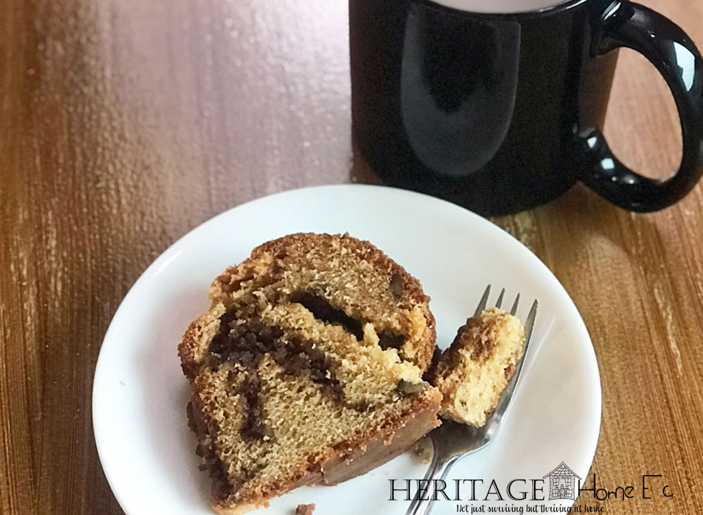 piece of coffee cake on wood table with a cup of coffee