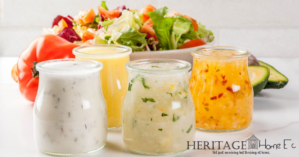 homemade salad dressings in little glass jars with bowl of salad
