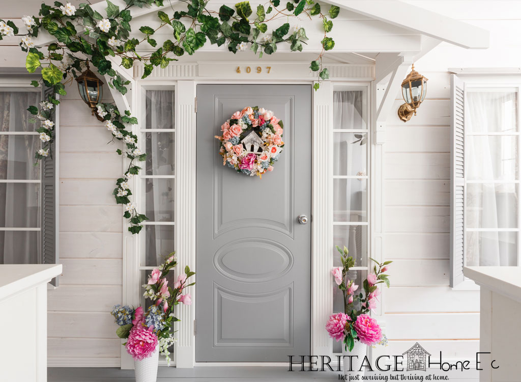 gray front door on white house with spring flowers and wreath
