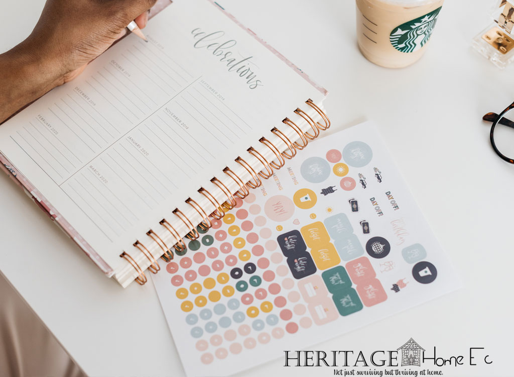 woman writing in planner with stickers and starbucks on white desk