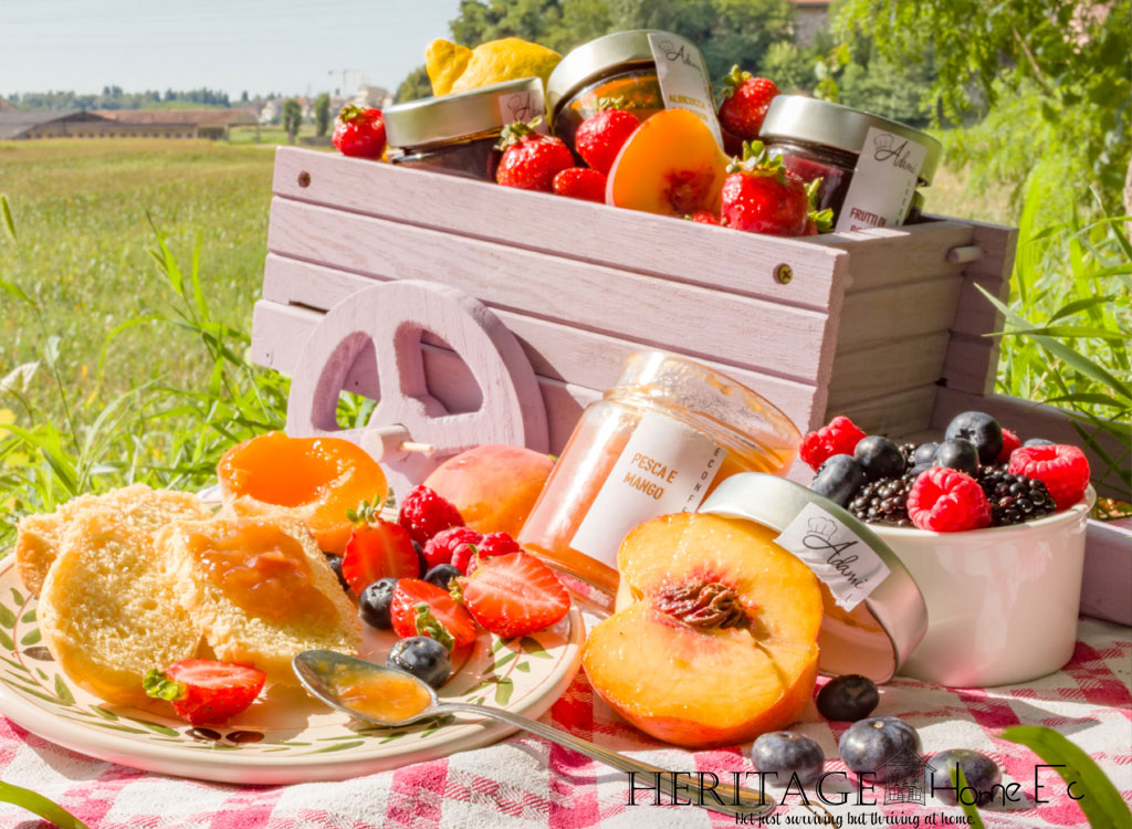 various jams in wooden wagon with fresh fruit and bread in a summer field for picnic