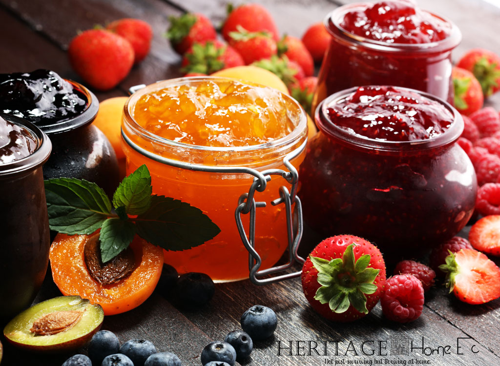 jars of jam with fresh fruit on a wood background