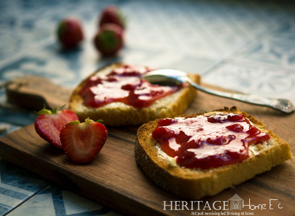strawberry jam spread on toast set on cutting board