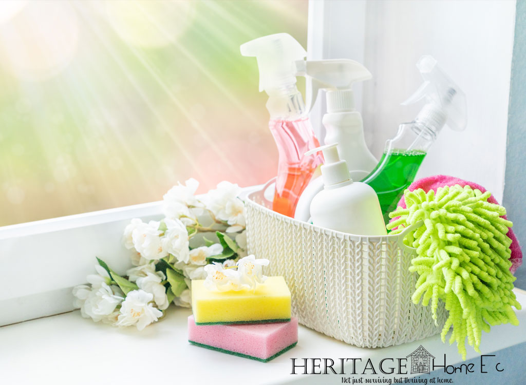 stocked cleaning caddy next to window with white flowers cleansers sponges