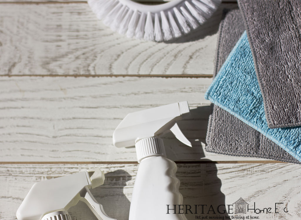 cleaning supplies and microfiber cloths on whitewashed wood background