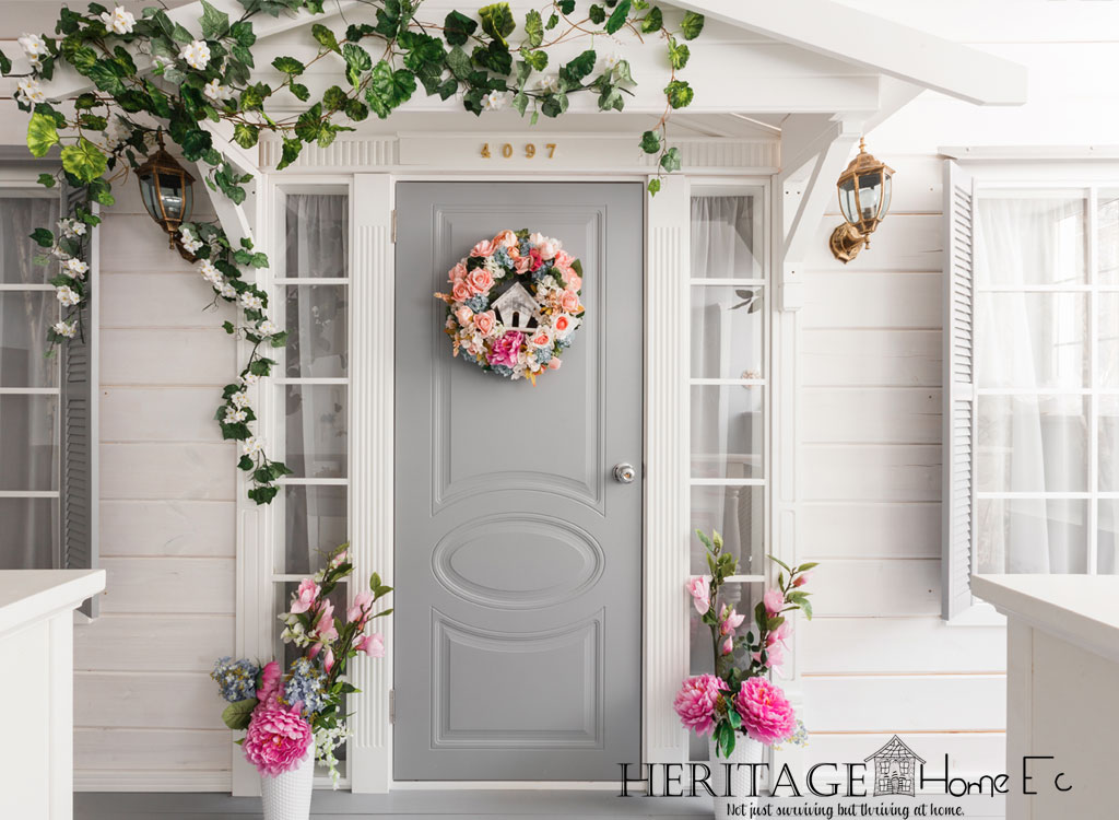 Pretty grey front door on white house with vines and flowers.