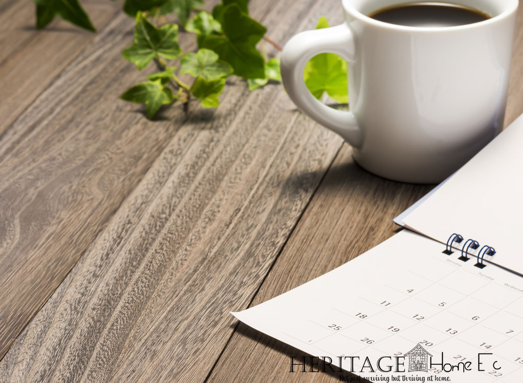 bound calendar with white mug of coffee and ivy on a wooden table