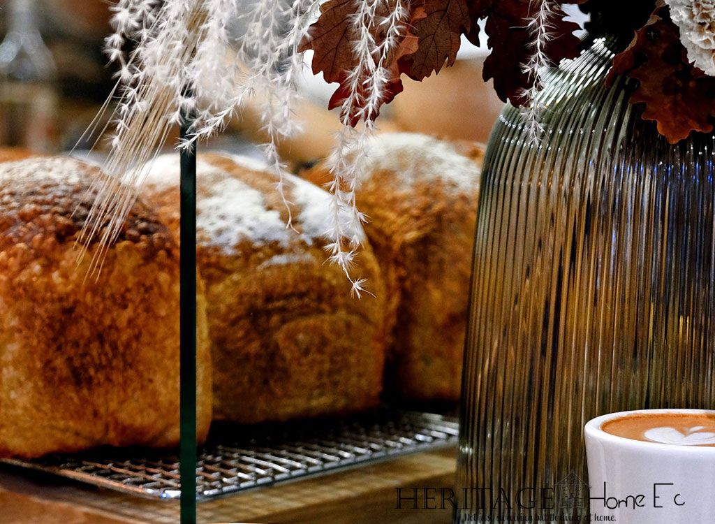 loaves of sponge cake on wire rack behind vase of fall leaves and coffee