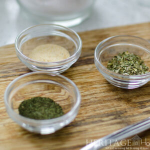 ground herbs in glass prep bowls on wooden cutting board