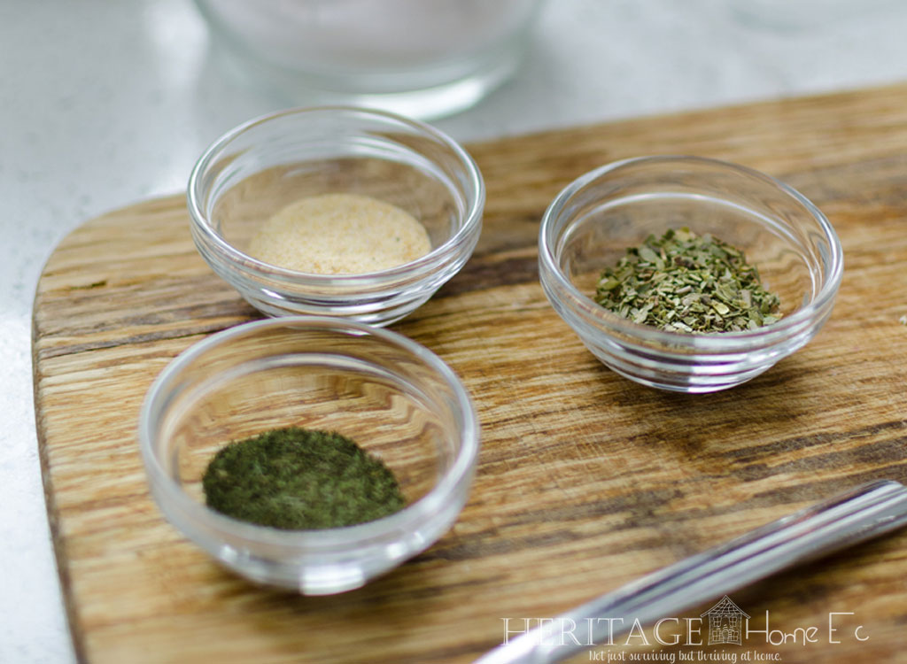 ground herbs in glass prep bowls on wooden cutting board