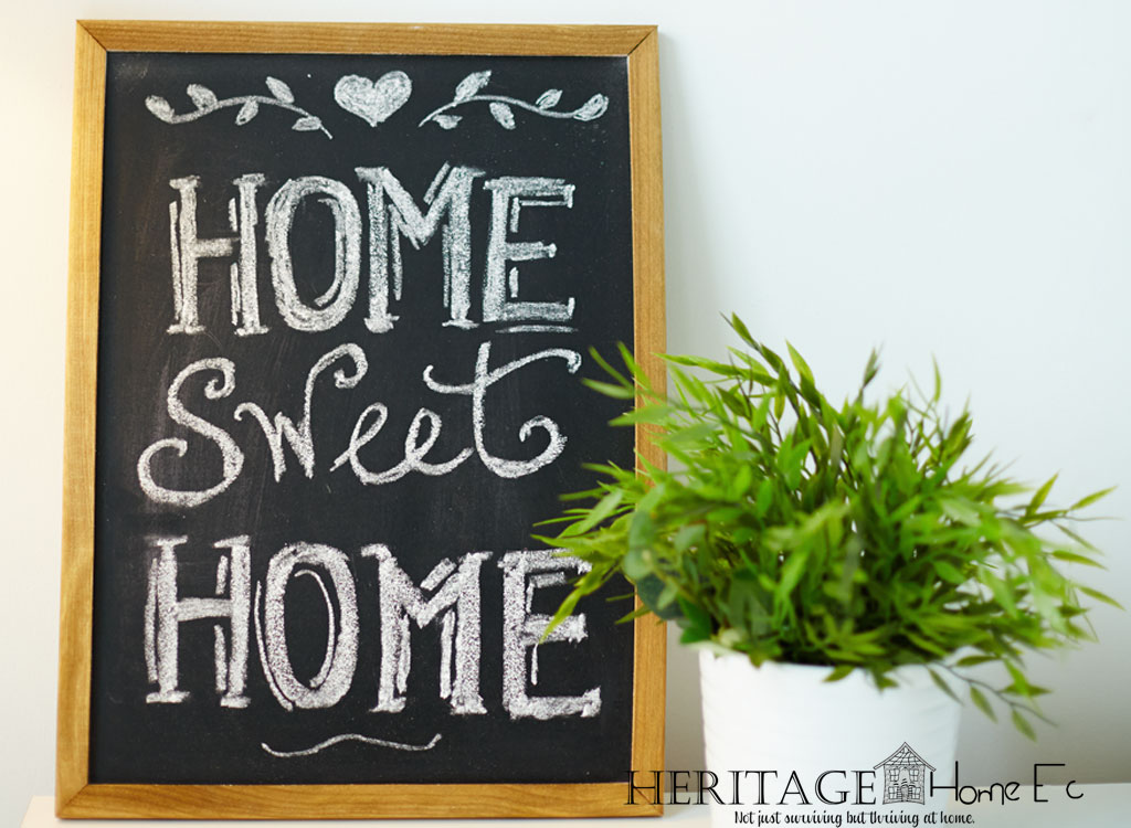 framed home sweet home chalkboard sitting on ledge with a potted houseplant