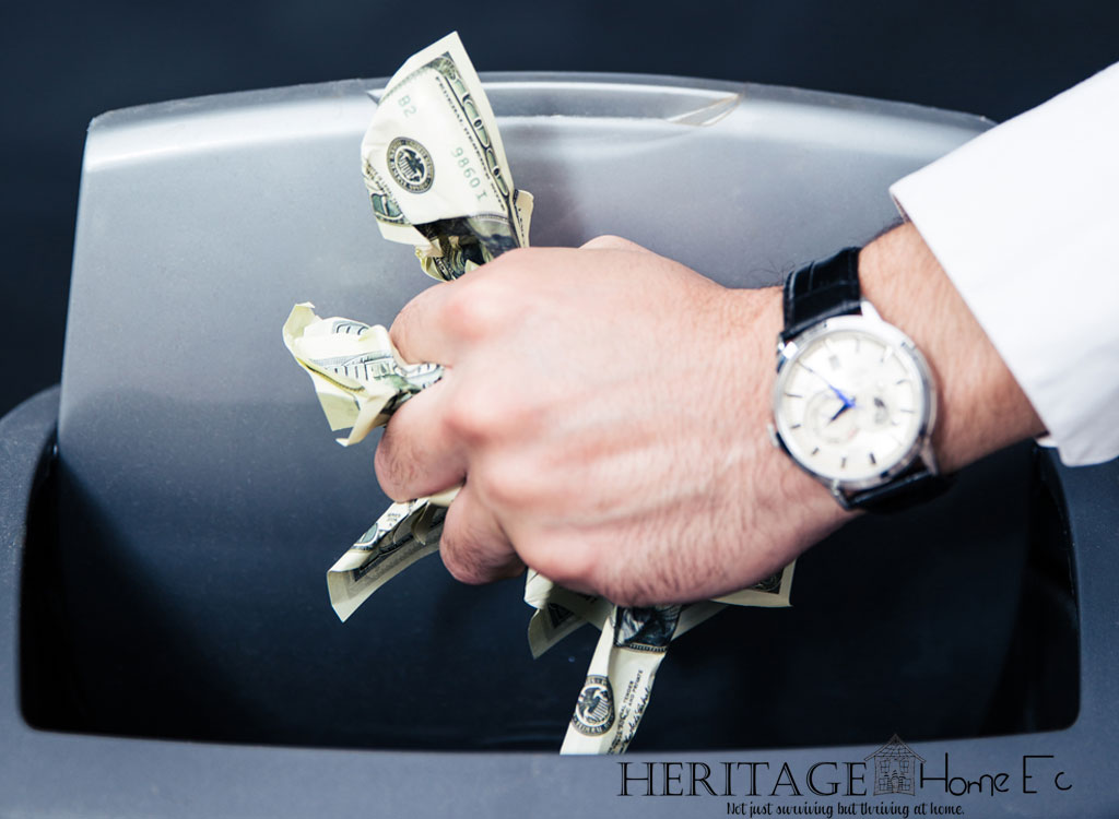 man with large wristwatch throwing a wad of money into a trashcan