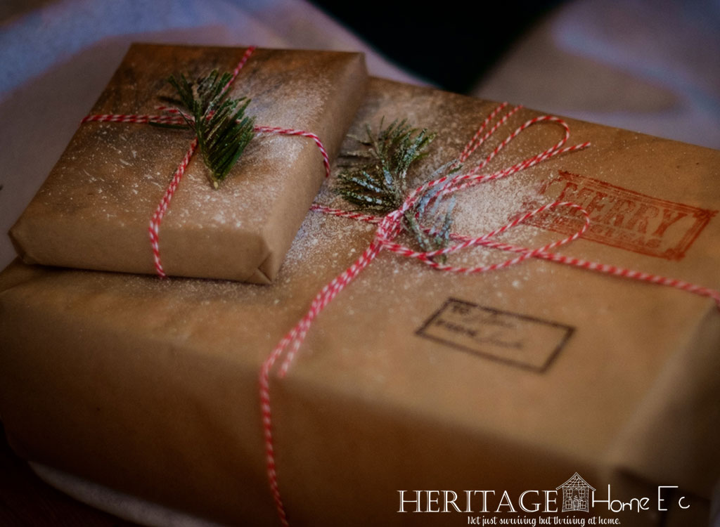 holiday packages wrapped in kraft paper tied with red and white twine and sprigs of evergreen