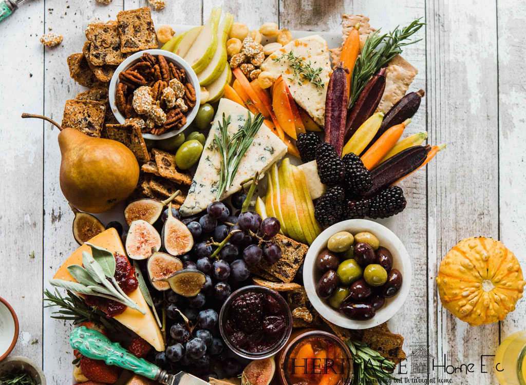 fall-themed chartreuse board with crackers, spreads, cheese, and fruit on a wooden backdrop with gourds