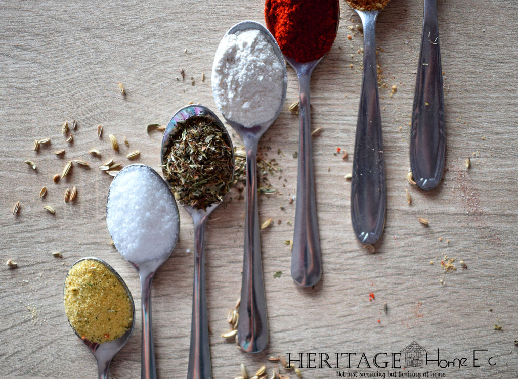 various herbs and spices in spoons on a wooden backdrop