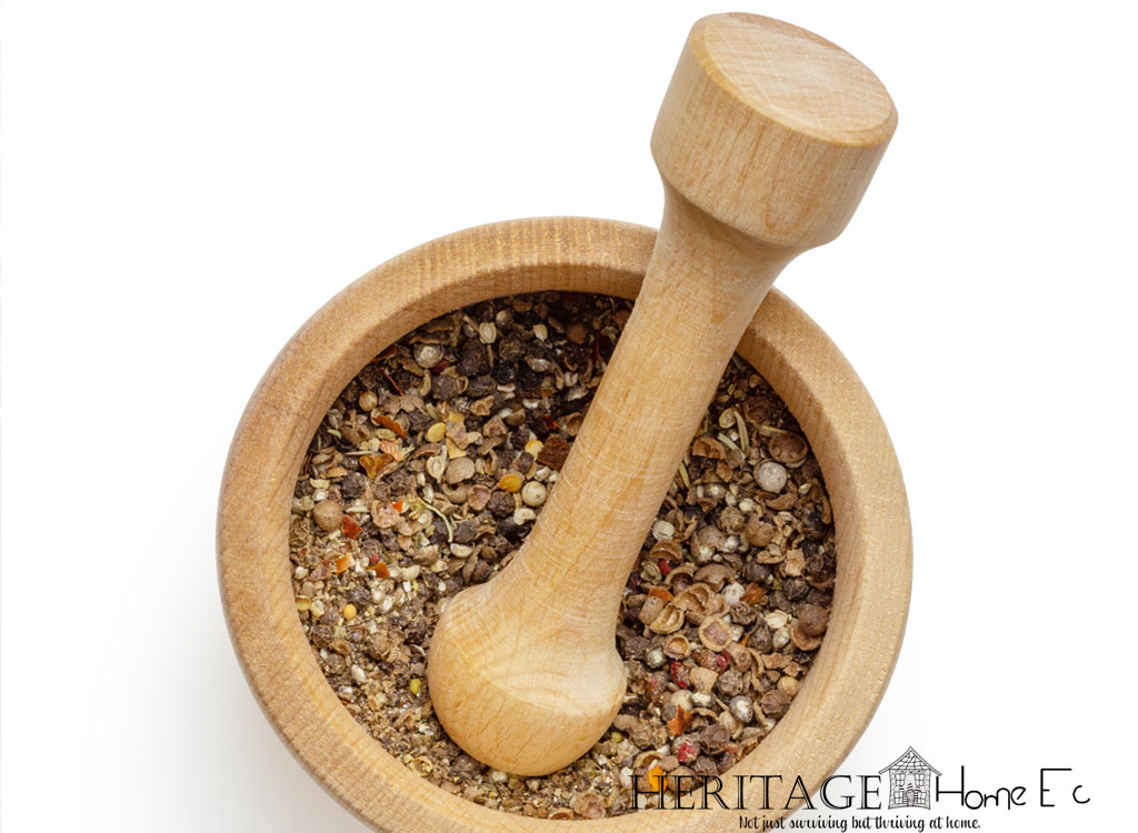 wooden mortar and pestle filled with herbs on a white background