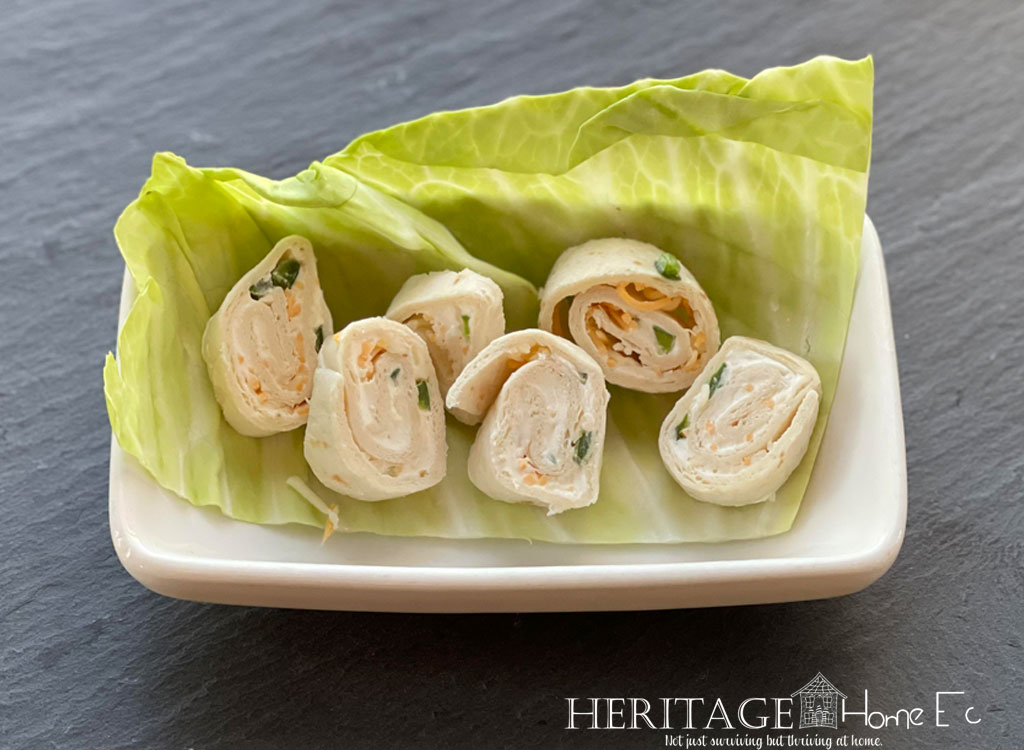 perfect party pinwheels in ceramic dish with garnish of cabbage leaf