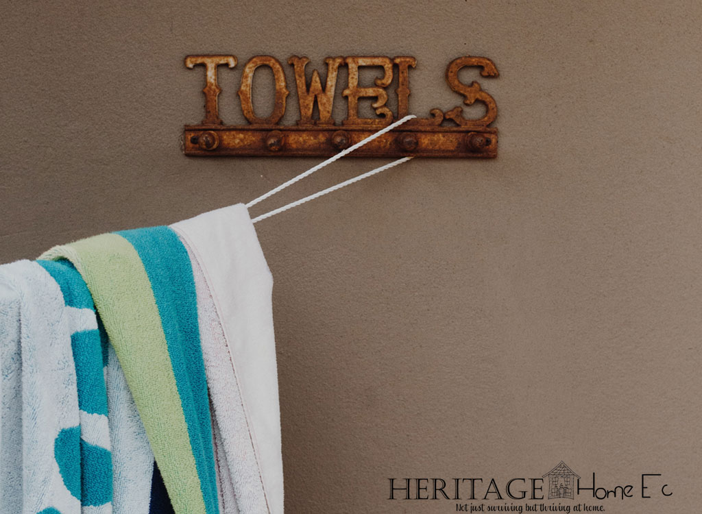 rusty metal towel hook sign on brown wall with beach towel hanging from looped clothesline