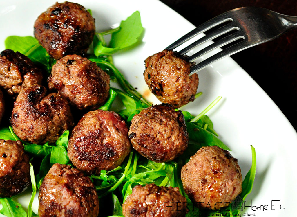 meatballs on white serving tray with a bed of spring greens
