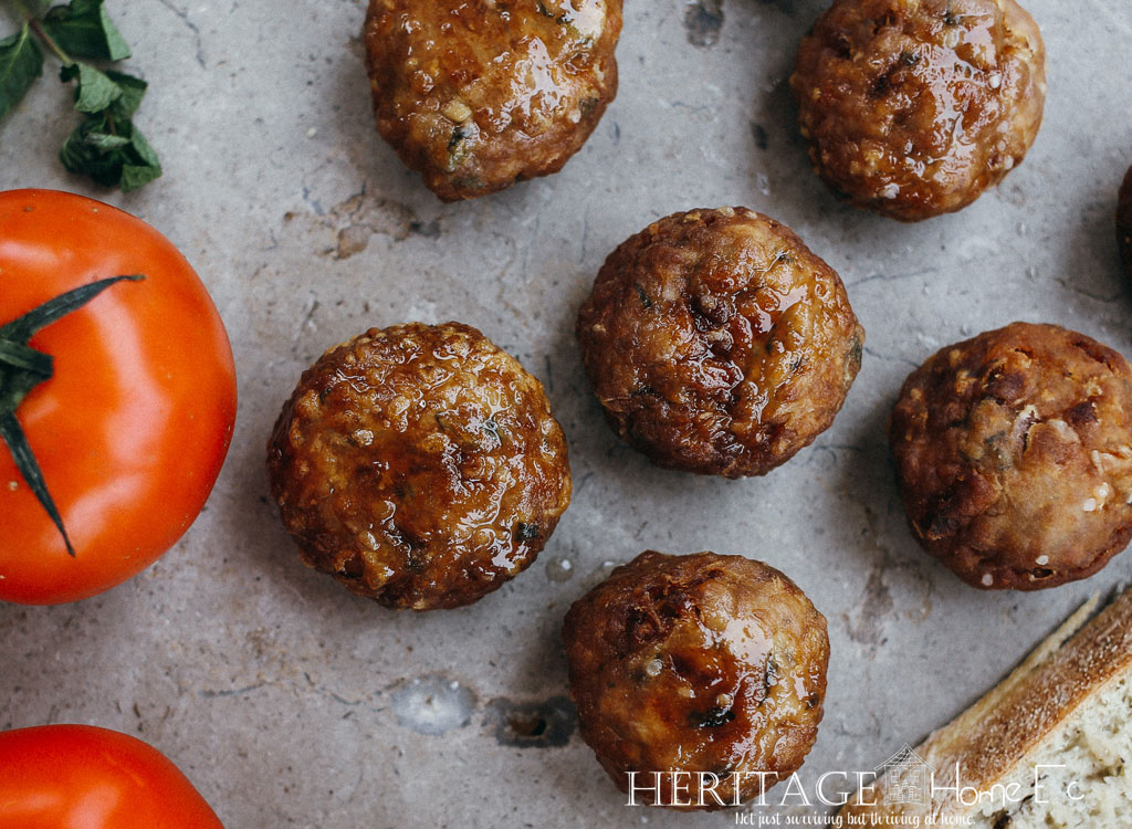 meatballs on stone background with crusty bread and vine ripened tomatoes